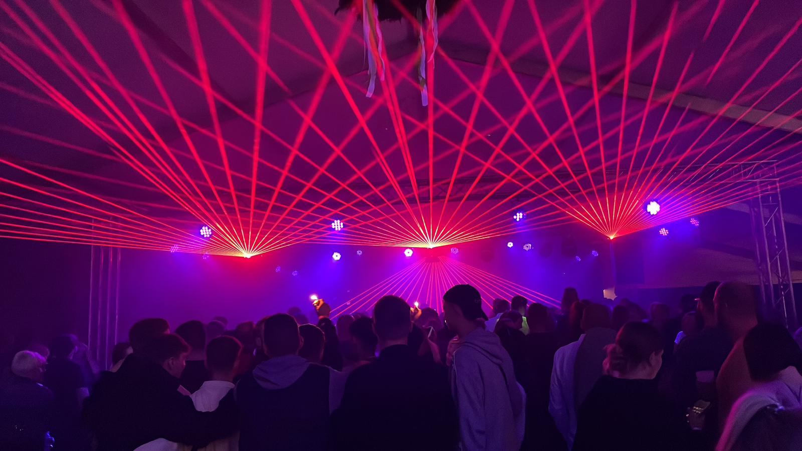 Rote Laserstrahlen über dem Publikum bei einer Lasershow auf einem Sommerfest