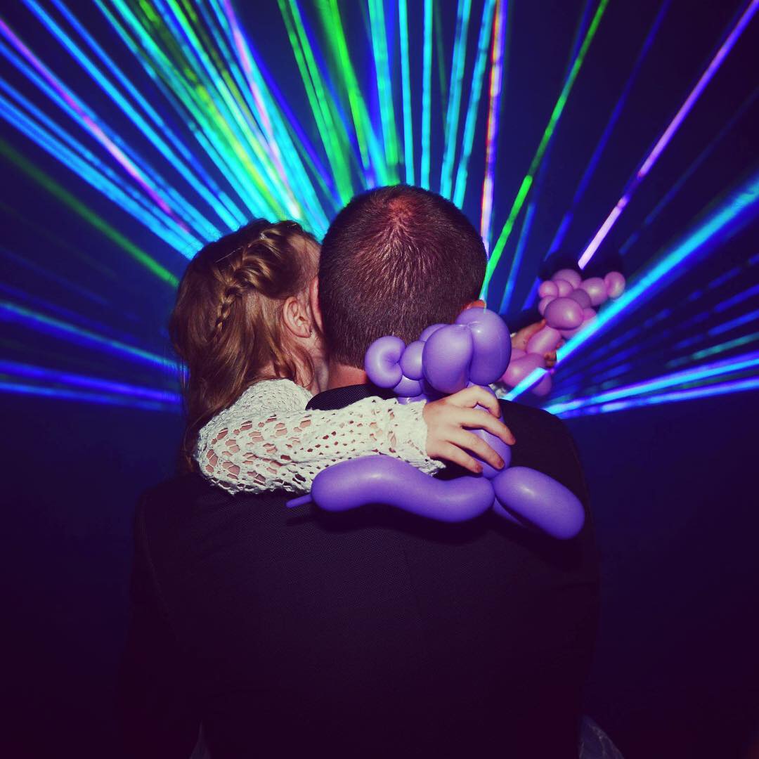 Vater mit Kind auf dem Arm vor bunten Laserstrahlen auf einer privaten Feier