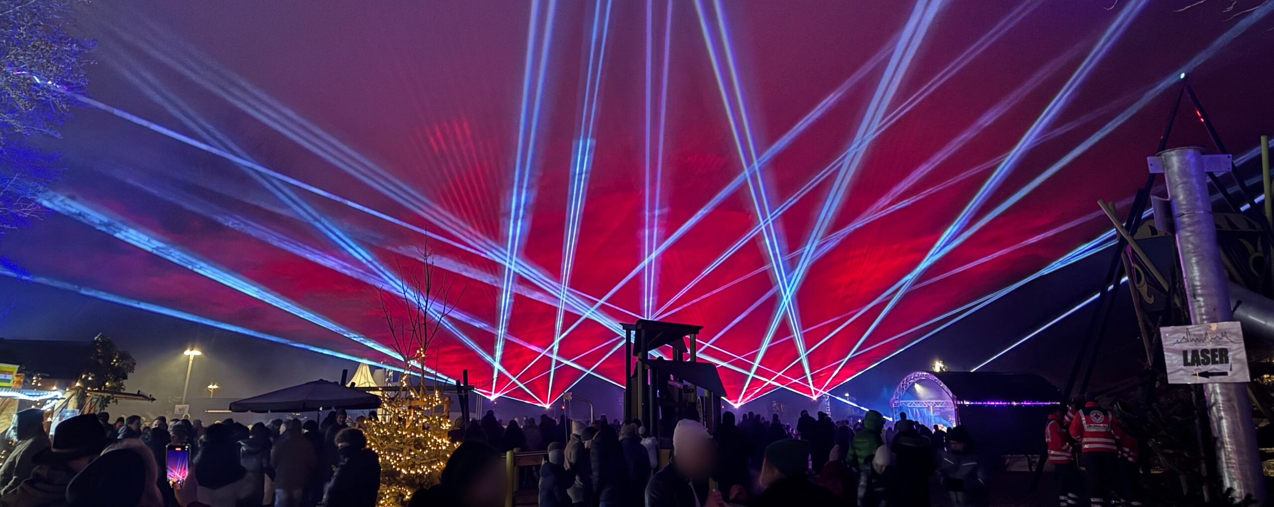 Laserstrahlen in Rot und Blau über dem Publikum bei einer Lasershow