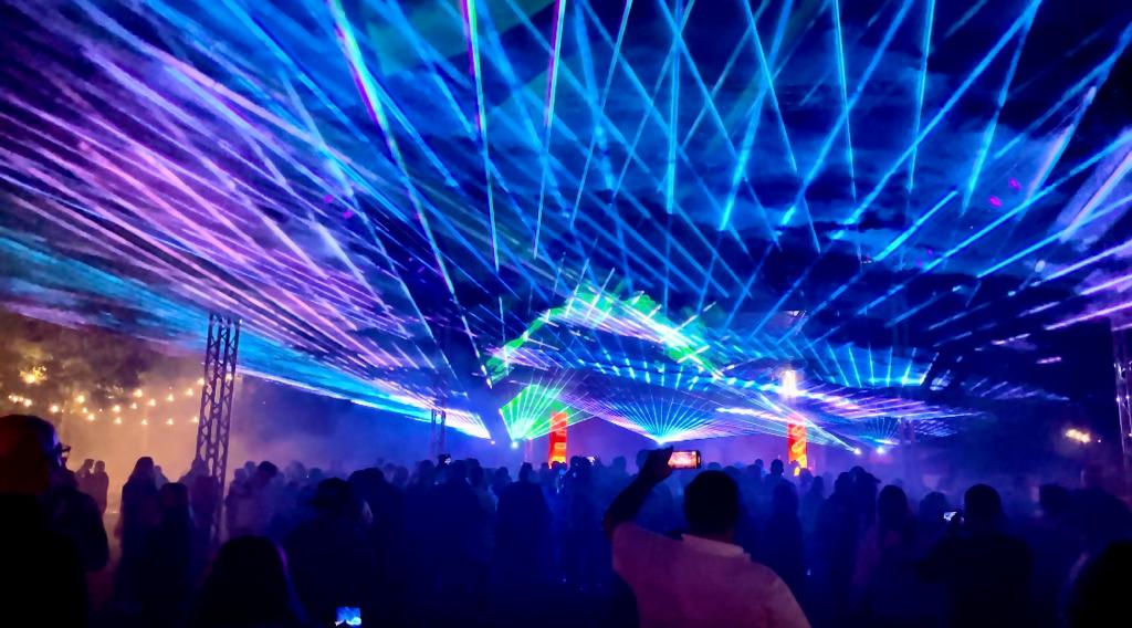 Blaue und grüne Laserstrahlen über der Bühne und dem Publikum bei einer Lasershow im Freien