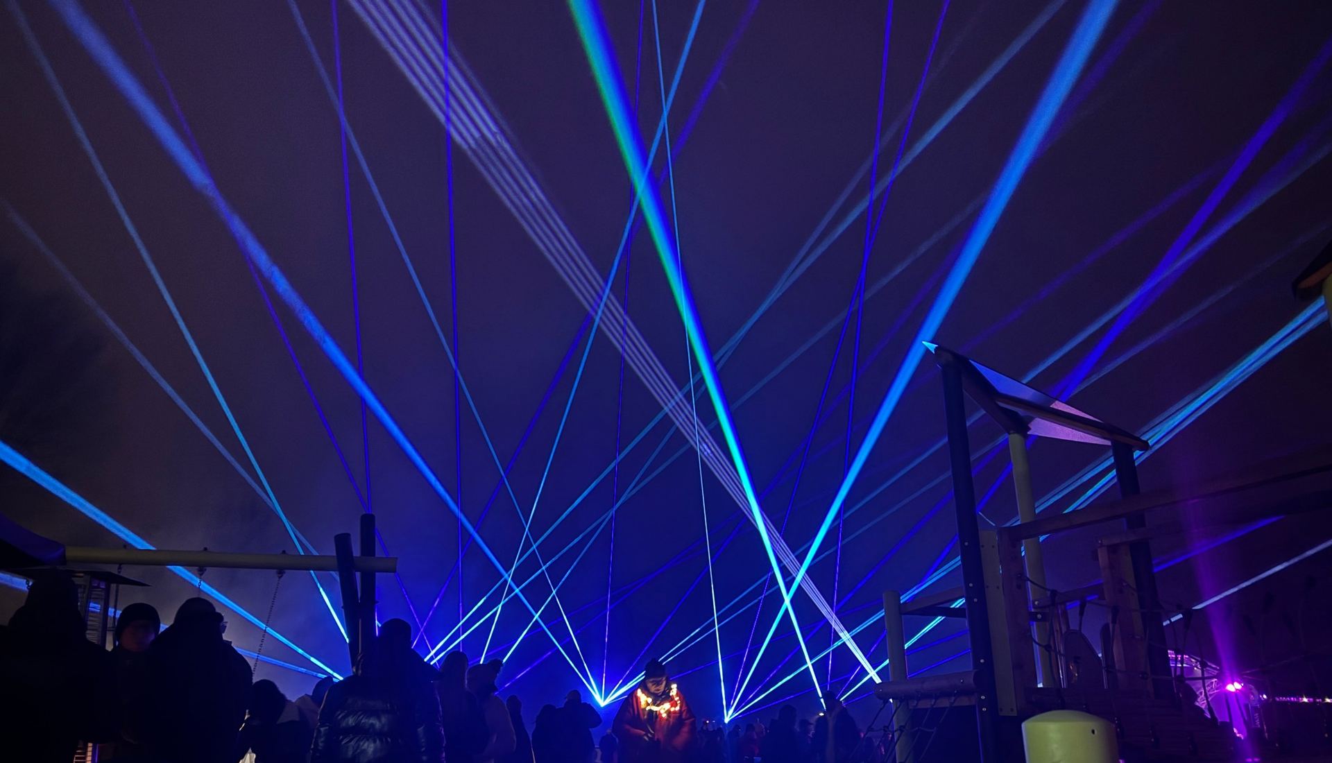 Blaue Laserstrahlen über dem Publikum bei einer Lasershow im Freien