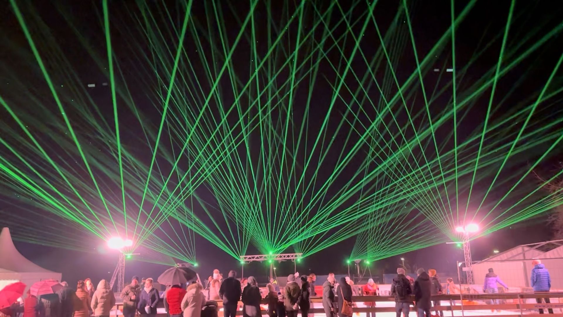 Grüne Laserstrahlen über einer Eisbahn bei einer Lasershow im Freien