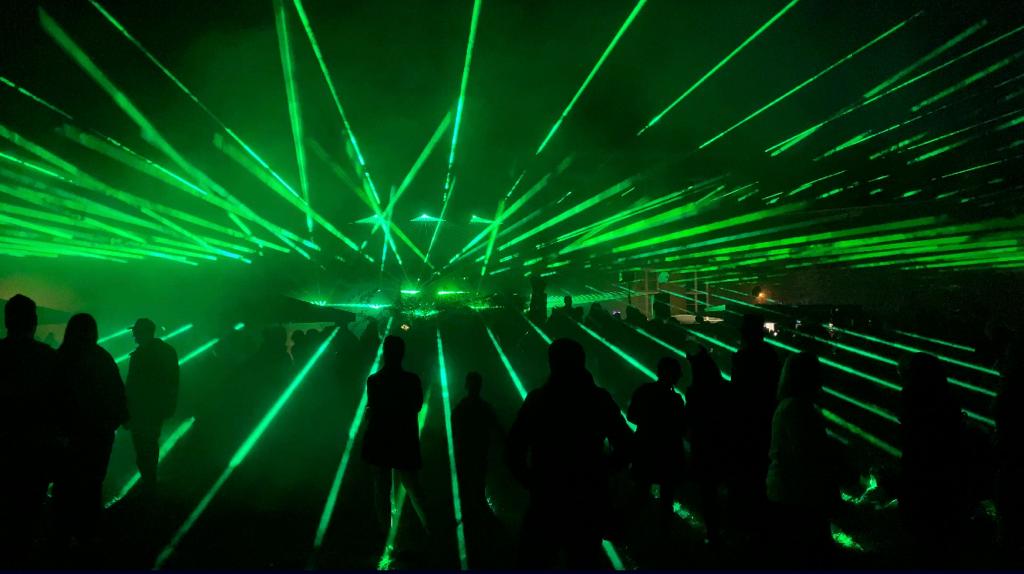Grüne Laserstrahlen über den Silhouetten des Publikums bei einer Lasershow