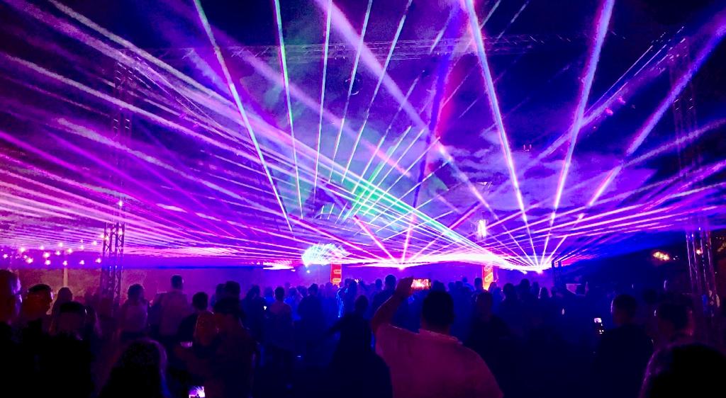 Lila Laserstrahlen über dem Publikum bei einer Lasershow im Freien