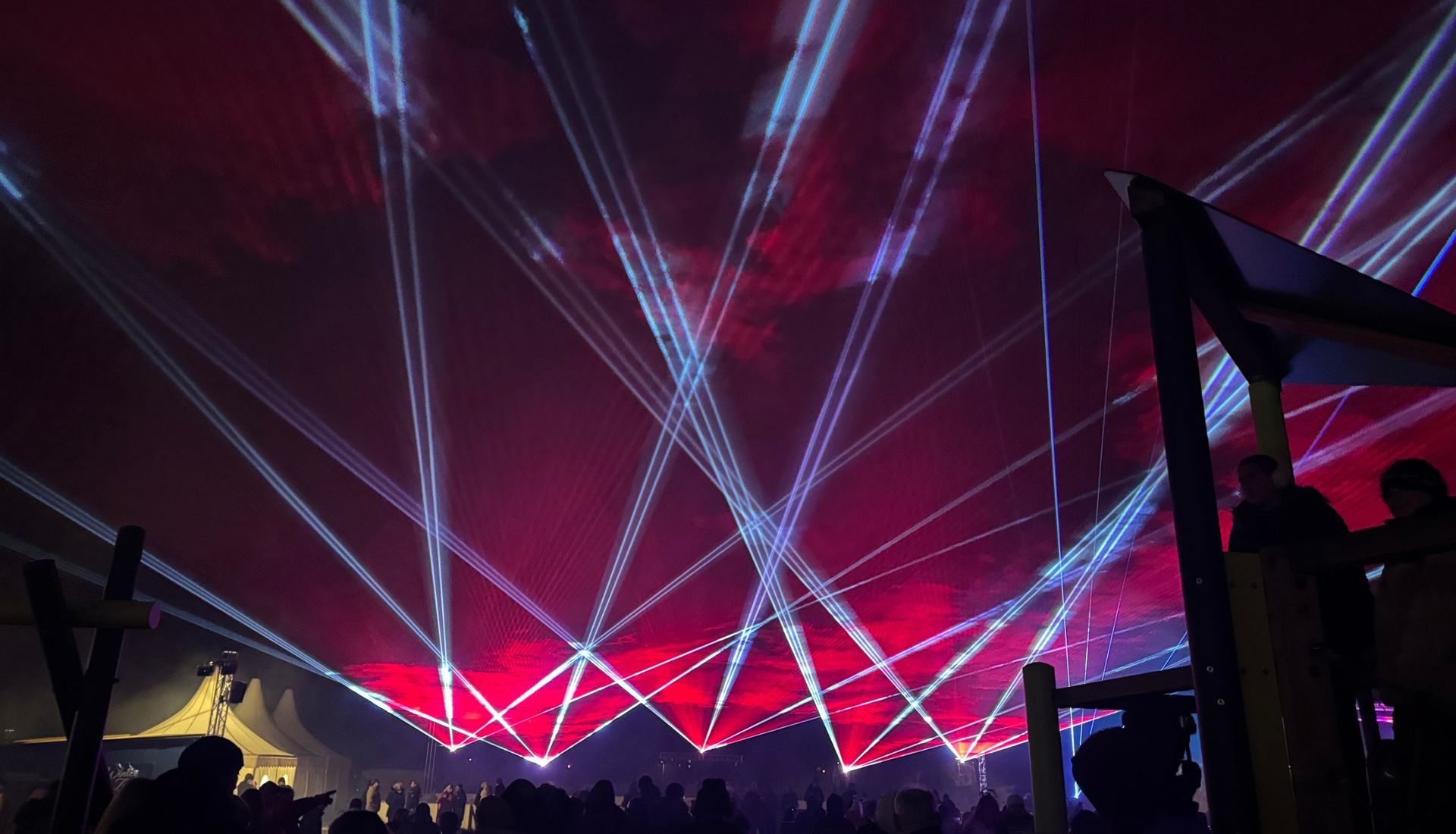 Rote und blaue Laserstrahlen über dem Publikum bei einer Lasershow im Freien